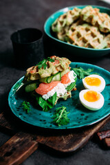 Belgian waffles with salmon, cucumber and egg in a plate