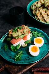 Belgian waffles with salmon, cucumber and egg in a plate