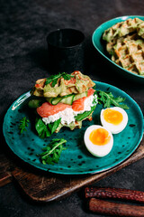 Belgian waffles with salmon, cucumber and egg in a plate