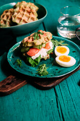 Belgian waffles with salmon, cucumber and egg in a plate