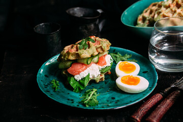 Belgian waffles with salmon, cucumber and egg in a plate