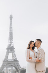 young european couple kisses near the Eiffel tower
