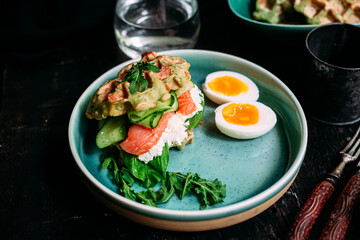 Belgian waffles with salmon, cucumber and egg in a plate