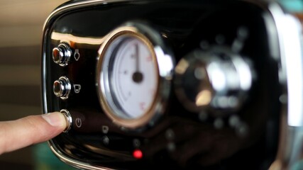 Close-up, man's hand pressing the power button of the coffee machine.