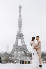 Wedding couple kissing in front of the Eiffel tower in Paris, France. A man kisses his woman.