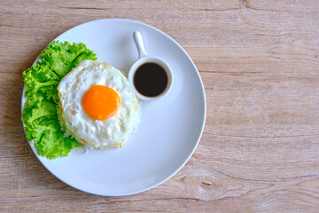 Fried egg rice on a white plate served with sauce and lettuce for healthy lovers.
