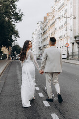 Young couple walks down the streets of France. Woman in a white dress and man in a suit.