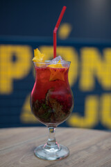 close up of a Red Cocktail on a wooden table with yellow letters in the background