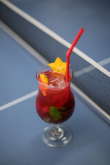 close up of a red cocktail on a blue table for background and a net for a ping pong game