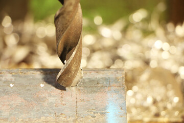 A drill for metal makes holes in a steel part on an industrial drilling machine.
