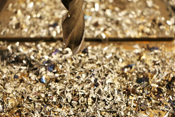 A drill for metal makes holes in a steel part on an industrial drilling machine.