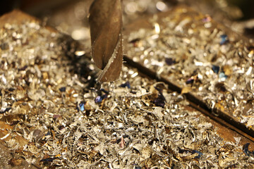 A drill for metal makes holes in a steel part on an industrial drilling machine.