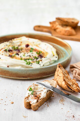 Feta with herbs, spicy honey and mini baguette on a plate on a rustic background. Vegetarian menu, healthy food.
