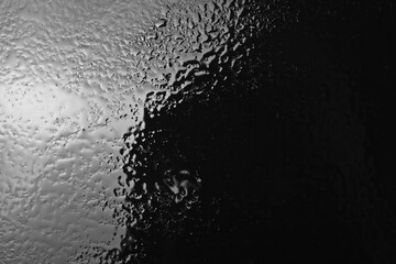 Water puddle and droplets isolated on black background and texture, top view