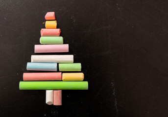 Christmas tree shape with colorful chalks on a school black board, copy space