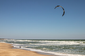 Water sport. Kite riding. Kitesurfing at sea. Board on the waves. Ride the waves. An athlete in a wetsuit. Extreme hobby. Kiteboarding as entertainment. The man in the water.
