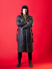 A man in old-fashioned clothes and a hat with earflaps, Russian post-war style.