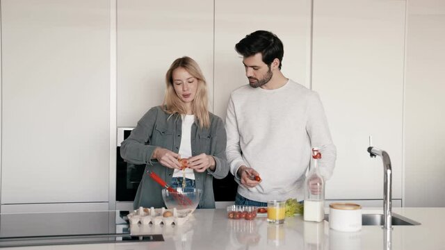 Cheerful couple preparing breakfast at home