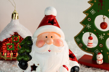 Table covered with snowflakes with Christmas decorations. Santa Claus, Christmas tree with red, gold balls and lights. Selective focus.