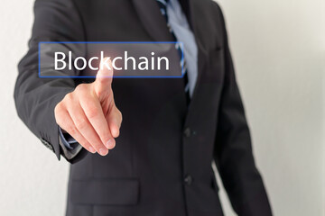 A businessmen is touching a virtual button on screen with Blockchain