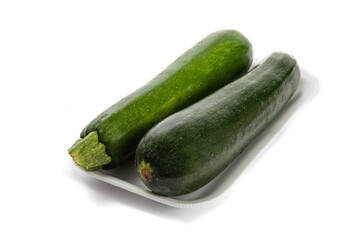 two green zucchini squash in a grocery store plastic foam tray isolated on white