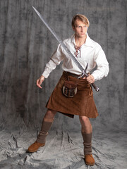 A young man in a leather kilt and a white lace-up blouse. combat stance.