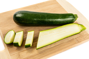 a whole green zucchini squash and a cut up zucchini showing the seeds isolated on white