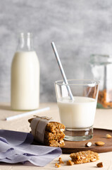 A glass and a bottle of milk with cereal bars, some almonds in a jar and a light blue napkin. 