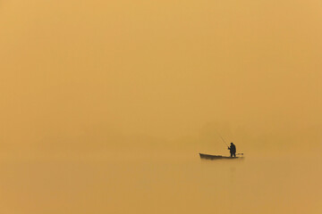 man fishing from boat at sunset