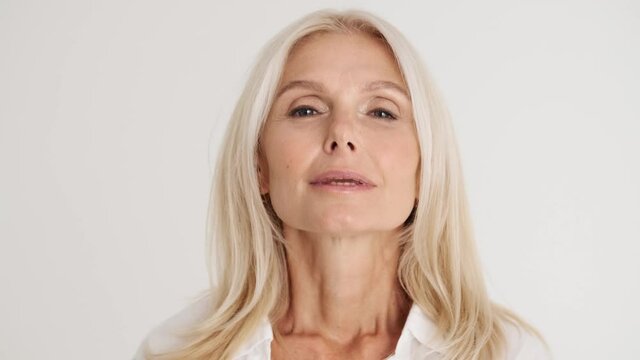 Close-up View Of The Concentrated Mature Woman Opening Eyes At The Camera And Breathing Out Heavily In The White Studio