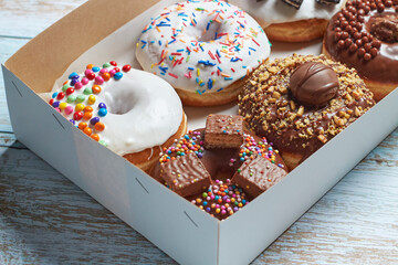 Caja de donas clásicas decoradas con diferentes topping o dulces.