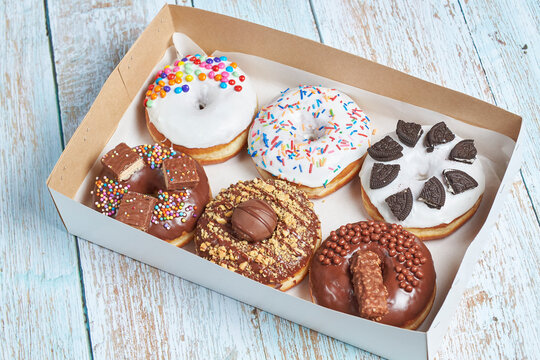 Caja de donas cl&aacute;sicas decoradas con diferentes topping o dulces.
