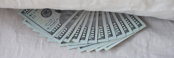 One hundred American dollar bills hidden under pillow