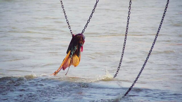 slow motion shot of colorful saffron orange cloth placed on a chain hanging into the ganga river at Haridwar to help people who fall in, placed as a mark of faith and decoration in this holy hindu