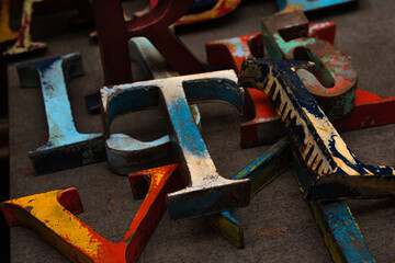 Random collection of colorful weathered wooden letters, numbers and characters for sale at flea market.