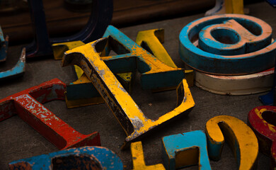 Random collection of colorful weathered wooden letters, numbers and characters for sale at flea market.