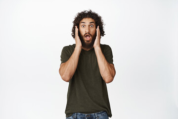 Image of overwhelmed shocked young man, screaming and looking startled at camera, seeing something impressive, white background