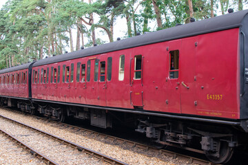 Obraz premium Sheringham, Norfolk, UK - SEPTEMBER 14 2019: Side of 1940s red passenger carriage attached to steam train