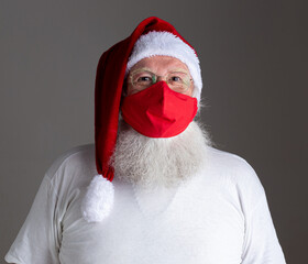 Santa Claus smiles behind red Covid-19 safety face mask. Christmas with social distance.