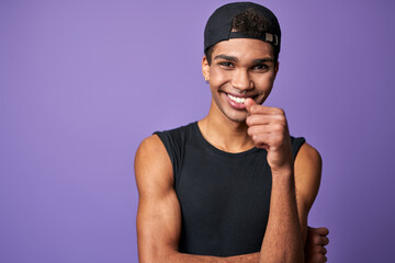 Portrait of smiling young brunette man in black t-shirt and cap. Happy latino model of trans gender - Powered by Adobe