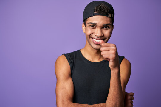 Portrait of smiling young brunette man in black t-shirt and cap. Happy latino model of trans gender