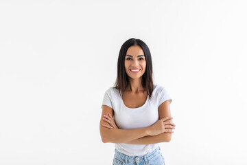 Young woman keeping arms crossed and smiling while standing isolated on white background