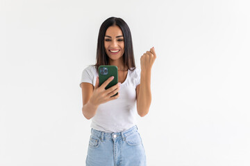 Fototapeta premium Portrait of a happy joyful woman holding mobile phone and celebrating a win isolated over white background