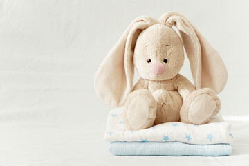 Baby shower. Long-eared hare on a blue background. Toy in the children's room. Children's bed. Favorite toy baby, children's background for birthday greetings.