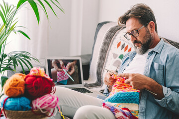 One adult man at home follow online knit tutorial to relax and enjoy resting home leisure activity...