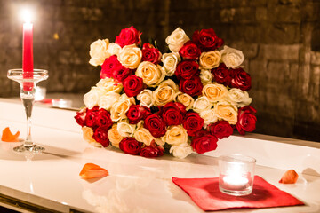 a bouquet of dark red roses stands in a glass vase on a beautifully decorated table.