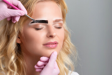 Make-up artist makes markings with white pencil for eyebrow and paints eyebrows. Professional...