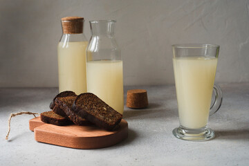 Still life with white kvass or sourdough in bottles and glass with slices of rye bread