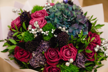 Colorful bouquet of different fresh flowers against brick wall. Bunch of orchids, roses, freesia and eucalyptus leaves. Rustic flower background.