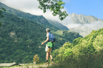 Middle age man walking in the mountain forest. Male with backpack do hike in the nature. Guy goes trekking outdoor in a beautiful park. Outdoors sport. Freedom, relax, leisure and lifestyle concept.